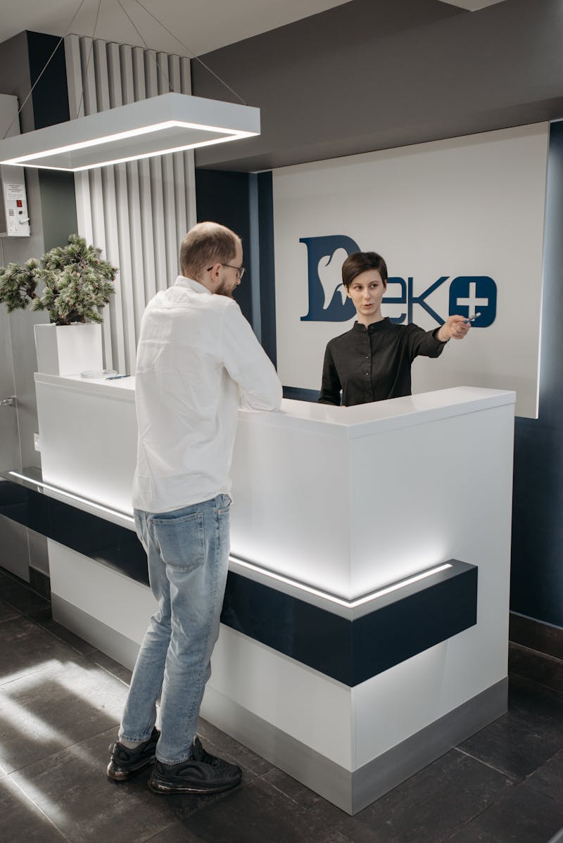 Modern dental clinic reception with receptionist assisting patient